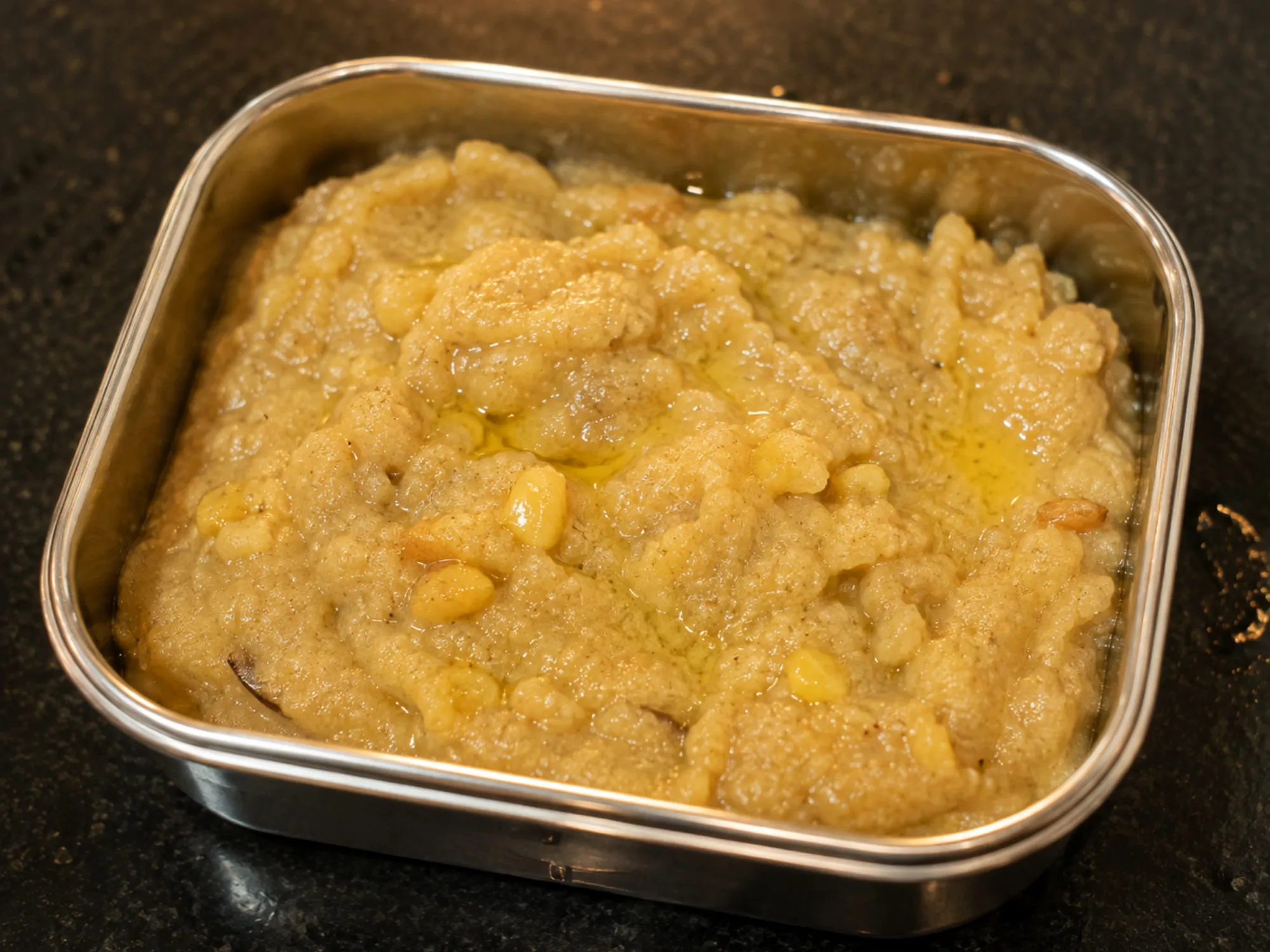 A small steel box of pale golden sheera, flecked with banana and finished with a little ghee